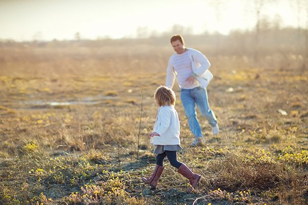 Father and daughter running on the grassy field