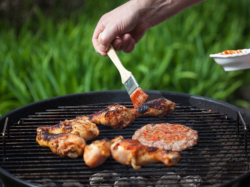 Applying BBQ sauce to meats with a brush