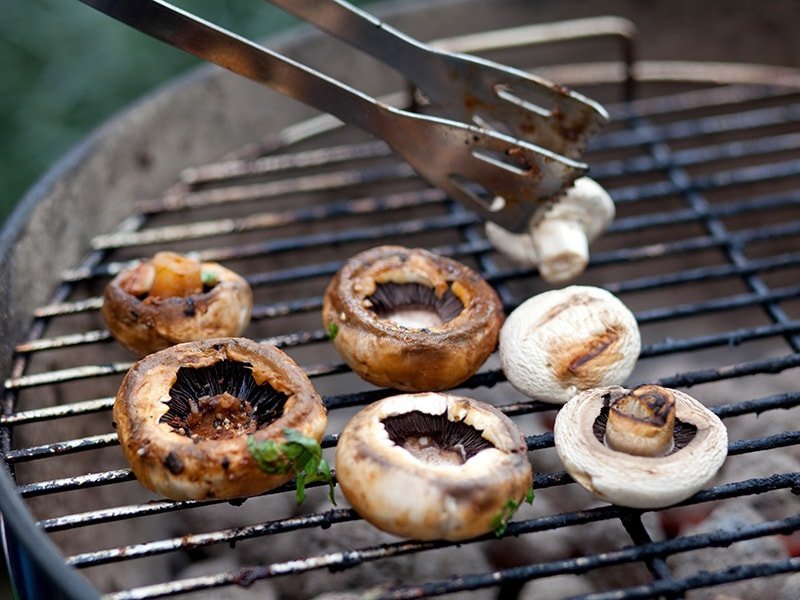 Grilling mushrooms on the bbq with tongs