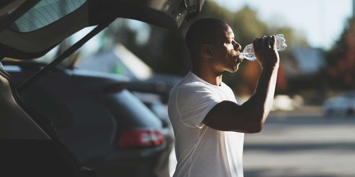 Tommy europe drinking a bottle of water by car