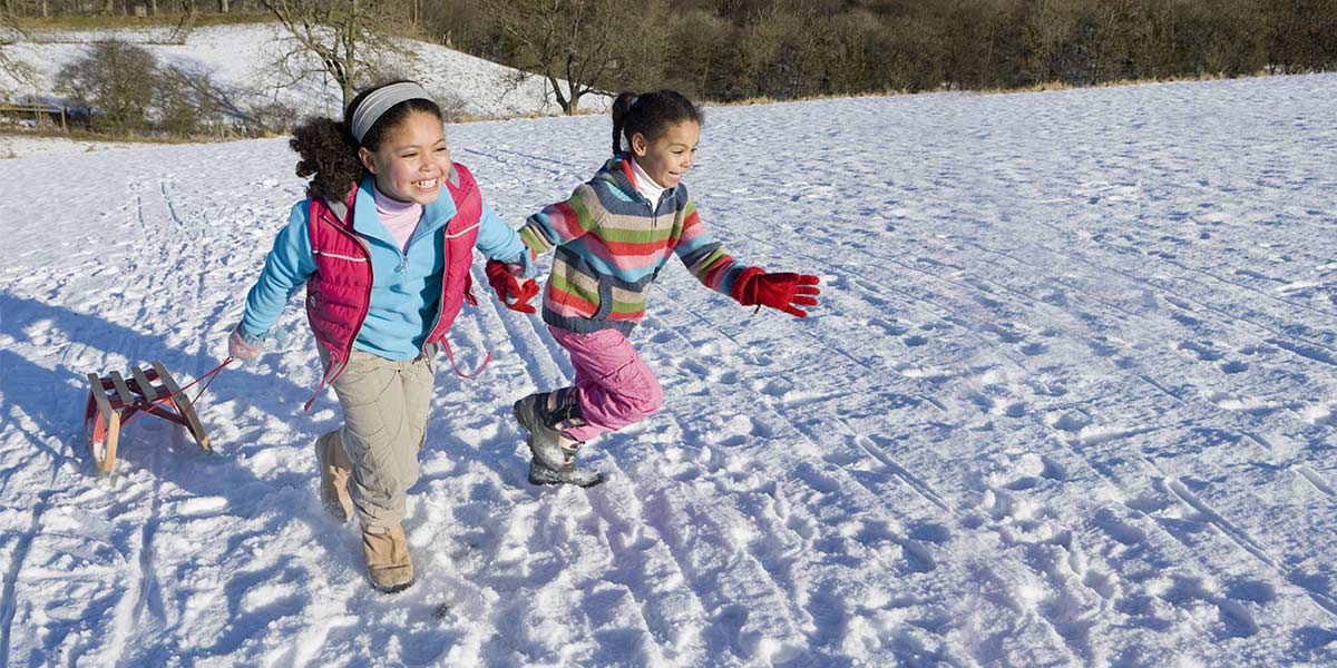 Two children running up a toboggan hill