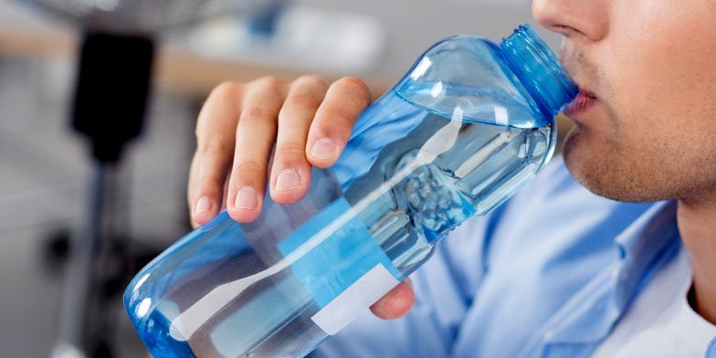 a man drinking from a water bottle at work