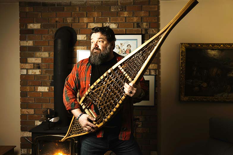 Toby hargrave carrying a snowshoe indoors