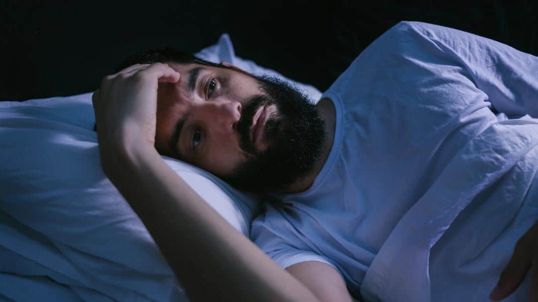 Man lying in bed awake