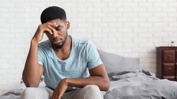 Anxious man sitting on bed