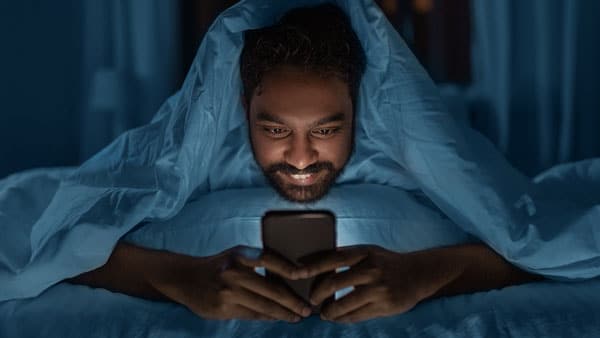 Man looking at cell phone in bed