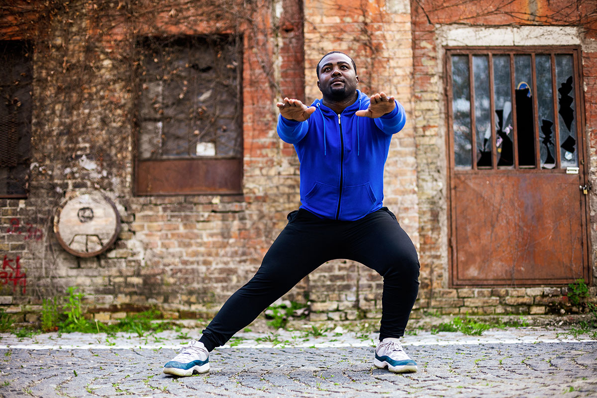 Man in blue hoodie doing side lunge