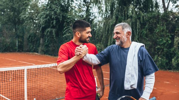 Two men shaking hands on outdoor tennis court