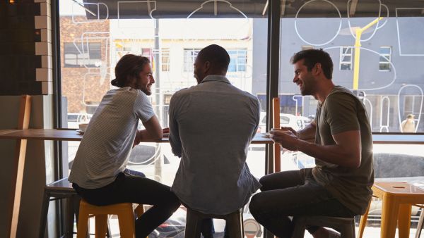 Three male friends hanging out in coffee shop
