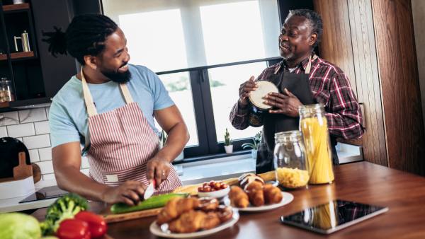 Two men in a kitchen chopping vegetables