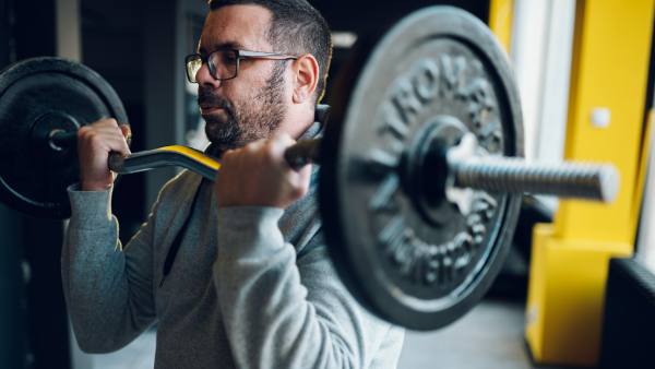 Man with glasses doing bicep curl with bar