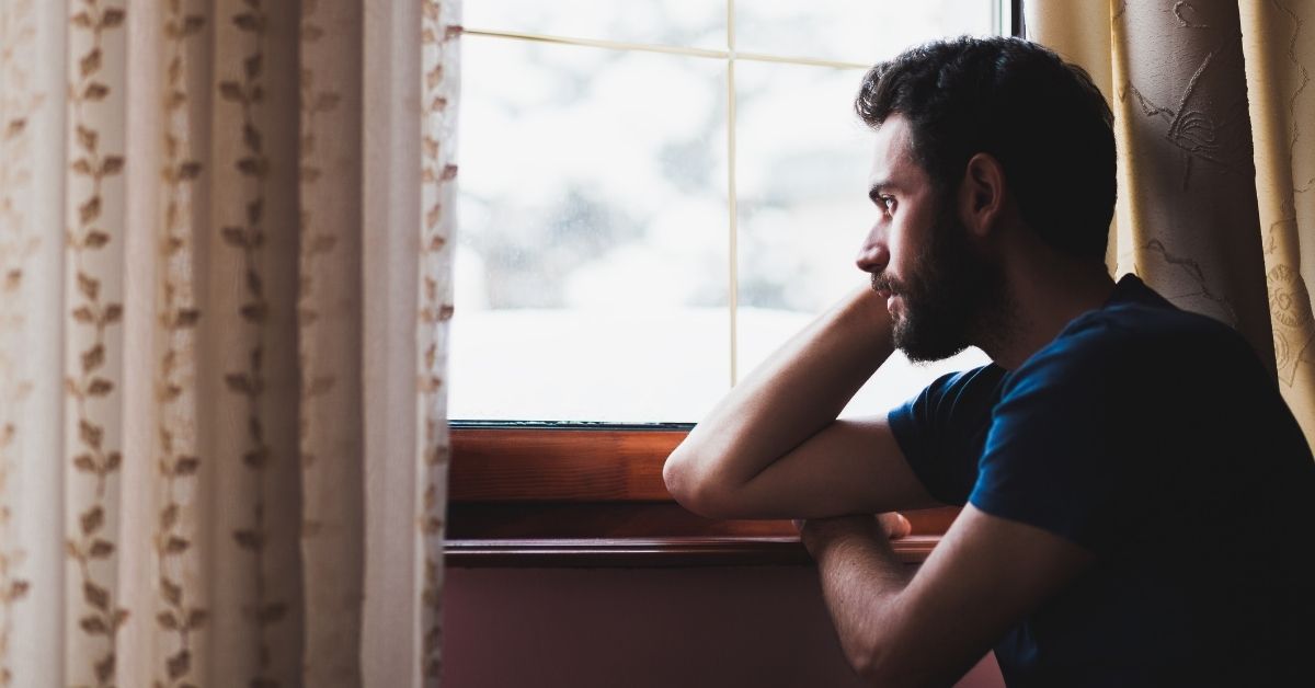 man looking at the window sad